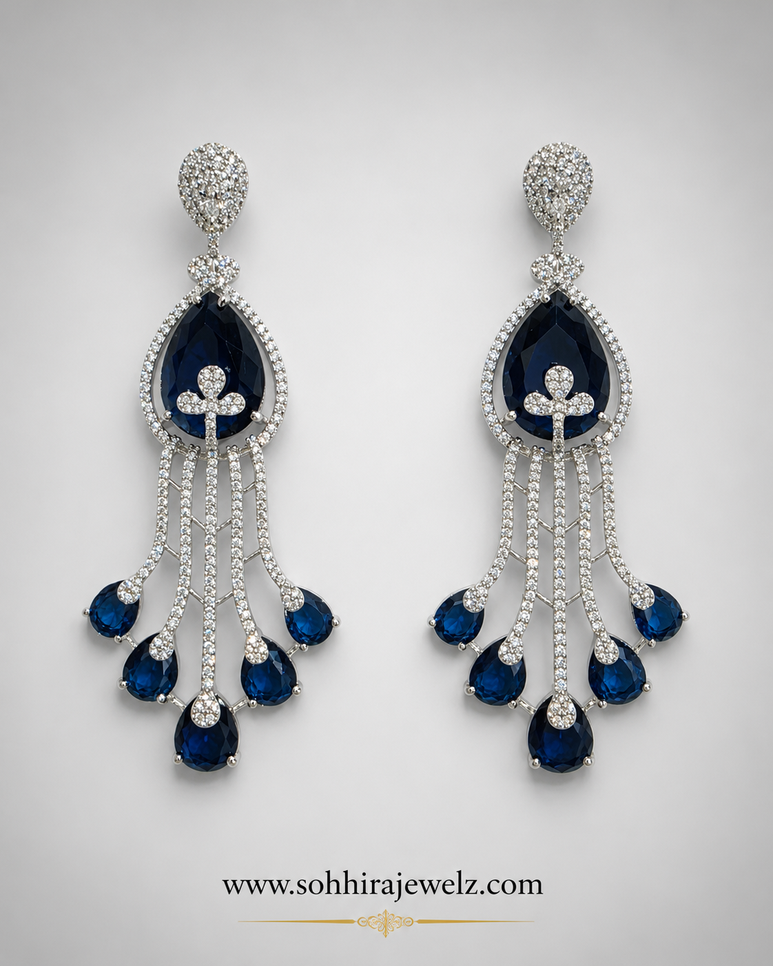 Sapphire Cascade Diamond Chandelier Earrings on luxury cream oval display stands with candles