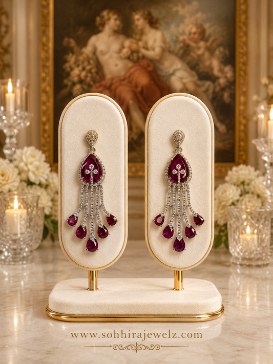Ruby Cascade Diamond Chandelier Earrings on luxury cream oval display stands with candles - front view