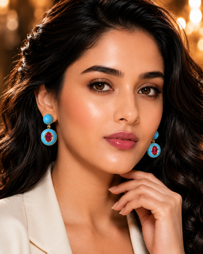 Turquoise Enamel Ruby Drop Earrings on luxury cream gold oval display stands in chandelier room