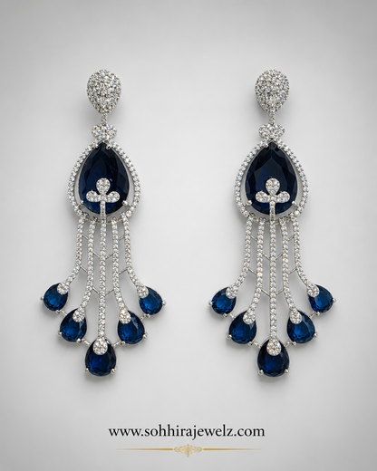 Sapphire Cascade Diamond Chandelier Earrings on luxury cream oval display stands with candles